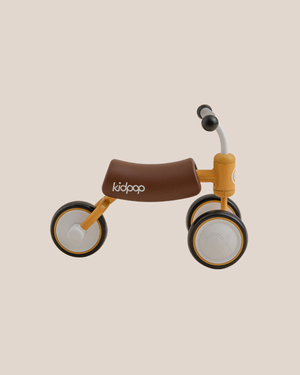 Yellow BEE Baby Balance Bike for toddlers with brown seat and white wheels, featuring 'kidpop' branding and modern design.