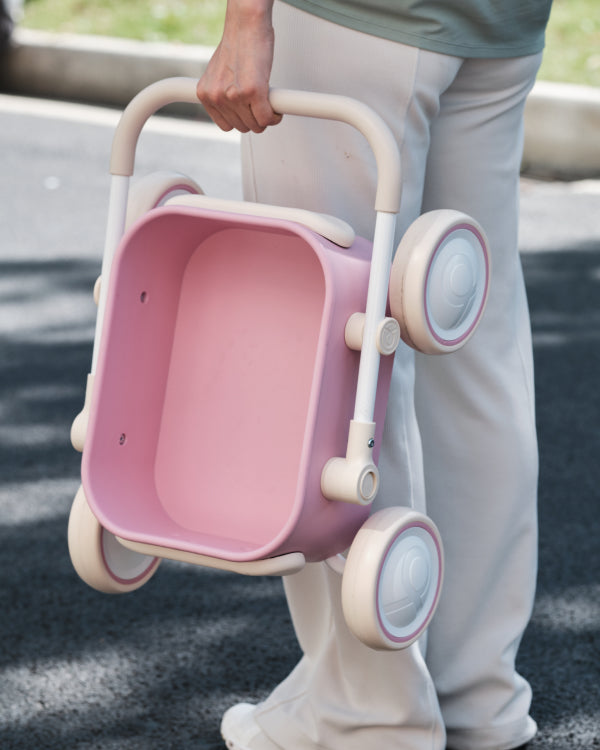 Pastel pink PULA Baby Push Walker Toddler Wagon with beige handle. Portable product appearance.