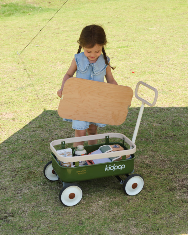 PULA-Wild 3-in-1 kids wagon in green with tan wheels, girl holding wood lid, showing contents for product page.