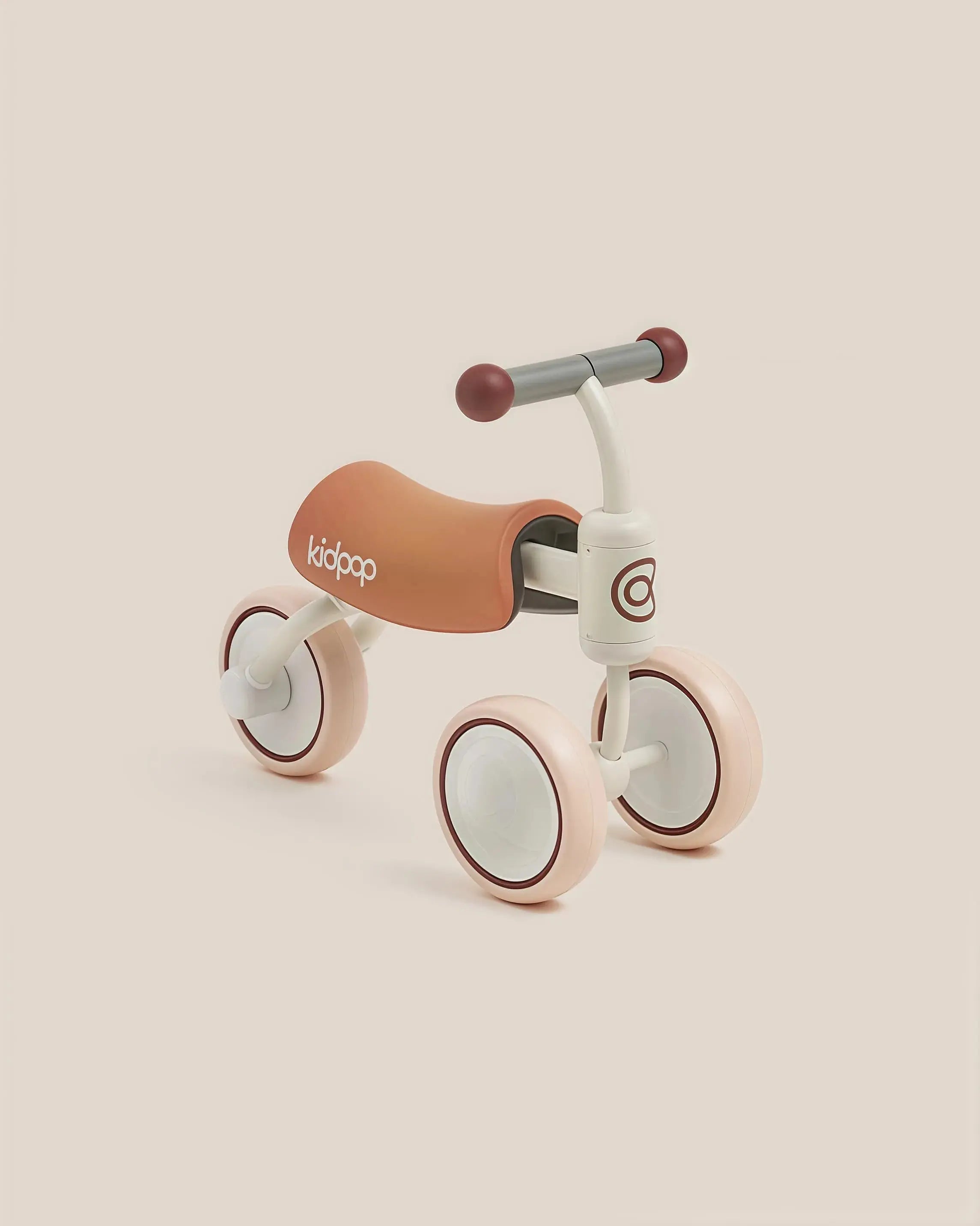 Light pink and tan BEE Baby Balance Bike for toddlers with 'kidpop' branding on seat, showcasing product appearance.