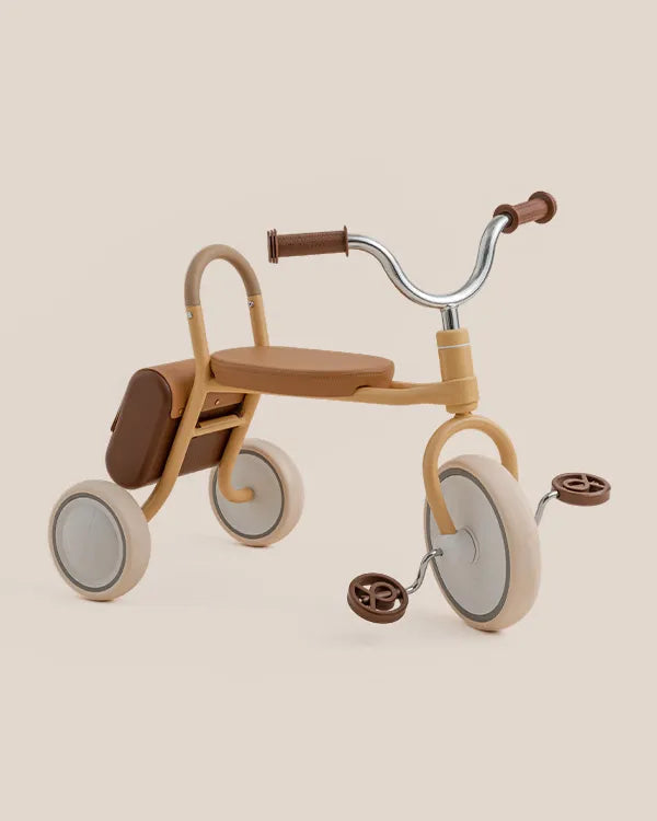 MATE Kids' yellow tricycle, a toddler riding toy, with brown seat, handlebars, saddle bag, and cream wheels.
