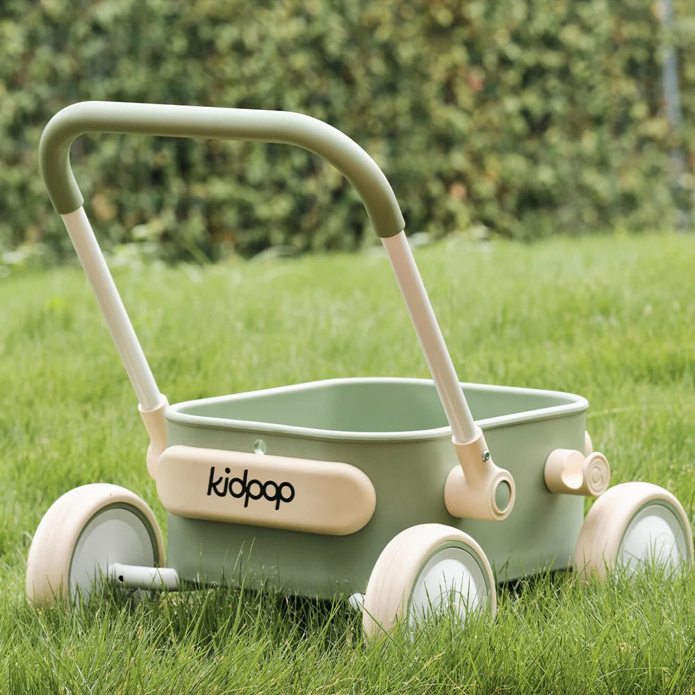 Kidpop sage green toddler wagon and walker on a lush green lawn.