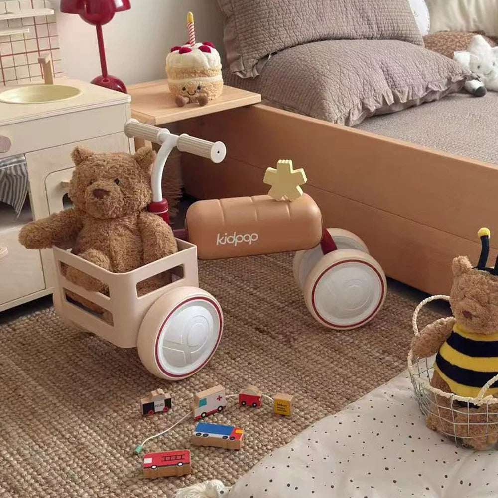 A Kidpop balance bike with a teddy bear in its basket, set in a cozy child's room.